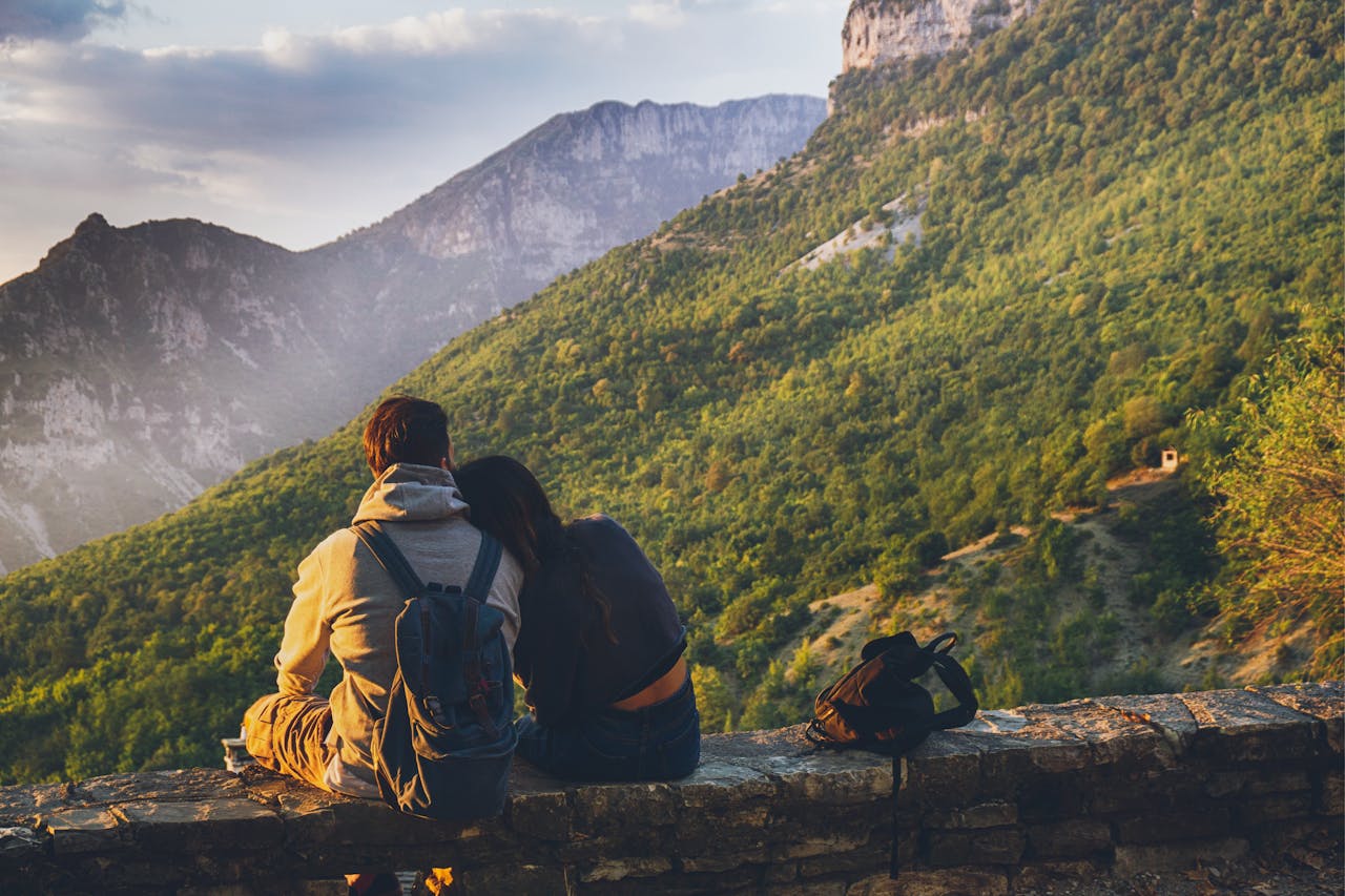 Couple sitting together enjoying a scenic mountain view at sunset, embodying love and adventure.